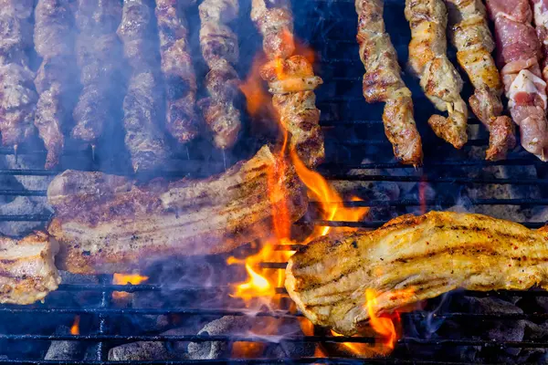 Şiş dolu bir ızgara ve ateşte pişmiş domuz eti. Et kahverengiler gibi duman yükselir, sahne geleneksel barbeküyü gösterir. Greek Souvlaki