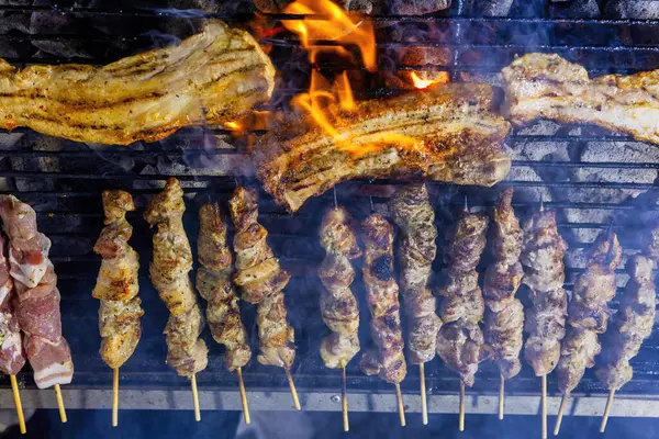 Şiş dolu bir ızgara ve ateşte pişmiş domuz eti. Et kahverengiler gibi duman yükselir, sahne geleneksel barbeküyü gösterir. Greek Souvlaki