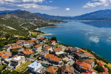 Yunanistan 'daki Polyfytos Gölü' nün sakin hava manzarası, yemyeşil tepeler ve sakin mavi sularla çevrili. Seyahat ve doğa severler için mükemmel huzurlu doğal bir manzara.
