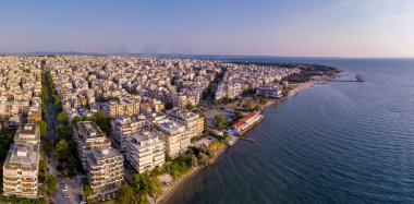 Yunanistan 'ın doğusundaki Selanik' in hava manzarası, açık mavi gökyüzü altında kıyı kentsel mimarisi, deniz ufku ve sakin şehir manzarası sergileniyor