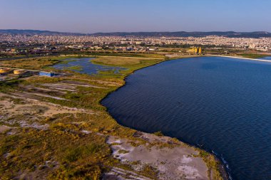 Selanik 'in batı kıyı şeridi ve Kalochori lagününün havadan görünüşü, kentsel yapılar, sanayi limanı ve sakin sulak arazi manzarasının harmanlanması.