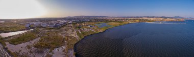 Selanik 'in batı kıyı şeridi ve Kalochori lagününün havadan görünüşü, kentsel yapılar, sanayi limanı ve sakin sulak arazi manzarasının harmanlanması.