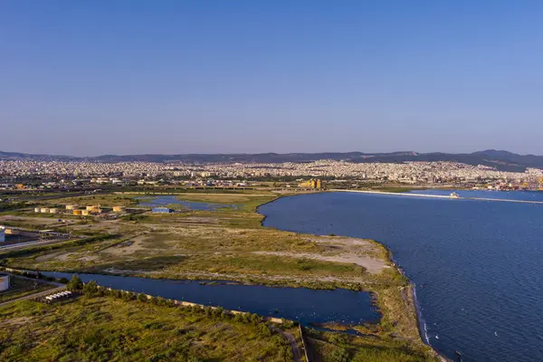Selanik 'in batı kıyı şeridi ve Kalochori lagününün havadan görünüşü, kentsel yapılar, sanayi limanı ve sakin sulak arazi manzarasının harmanlanması.