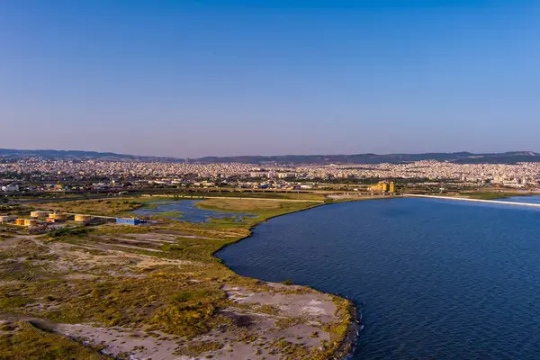 Selanik 'in batı kıyı şeridi ve Kalochori lagününün havadan görünüşü, kentsel yapılar, sanayi limanı ve sakin sulak arazi manzarasının harmanlanması.