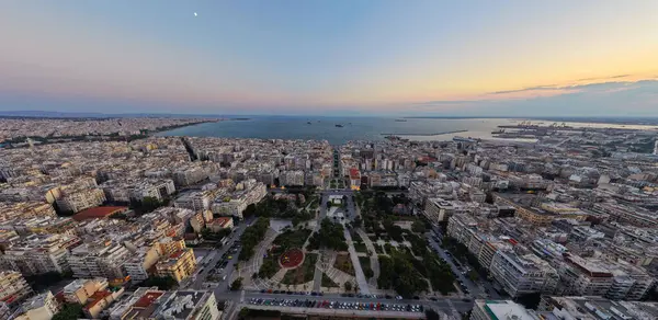 Selanik, Yunanistan 3 Ağustos 2025 - Selanik şehir parkı, şehir binaları ve termaik körfez kıyılarını altın saat olarak gösteren panoramik hava manzarası.