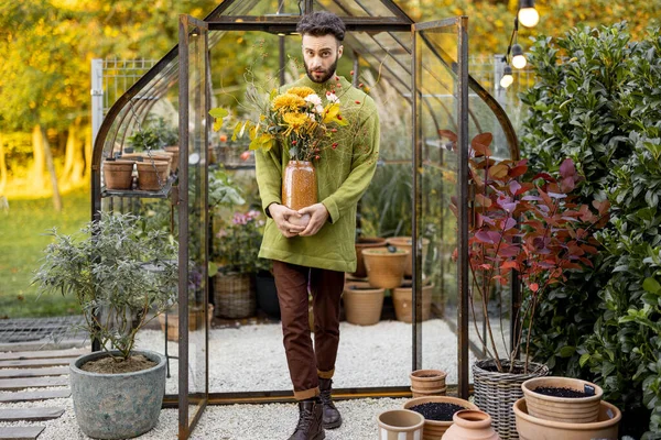 一个男人花匠的画像 他站在花园的小温室前 一束美丽的花朵 花卉及花卉工作坊的概念 — 图库照片