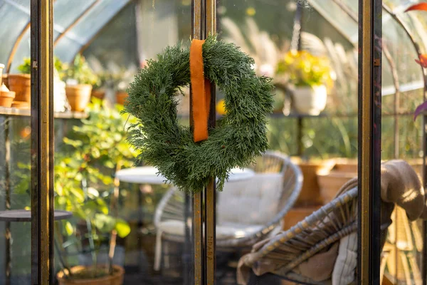 庭のヴィンテージ温室のドアにぶら下がっている美しい緑の花輪 — ストック写真