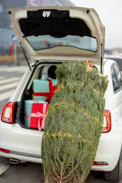 装在汽车行李箱旁边装饰有花环的圣诞树 外面放满了礼品盒 寒假和购物的概念 — 图库照片