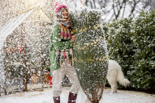 在一场雪天里 年轻的女人背着被包裹着的圣诞树 准备装饰她的房子 寒假快乐与魔法的概念 — 图库照片