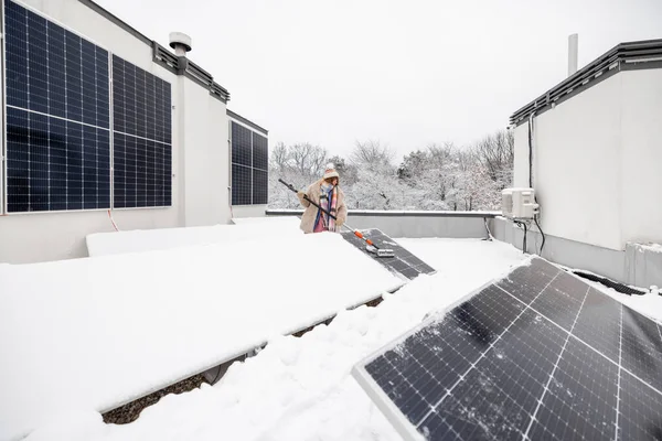 Kobieta Czyści Panele Słoneczne Śniegu Aby Zimą Wytwarzać Energię Dachu — Zdjęcie stockowe