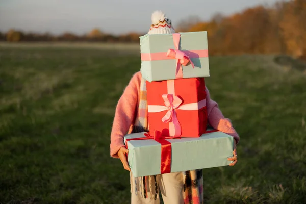 休日のために身を包んだ若い女性は 日没の間に自然の中で屋外で新年の贈り物を運ぶ 冬の休暇を見越して 準備とショッピングのコンセプト — ストック写真