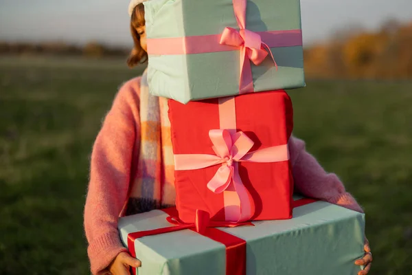 休日のために身を包んだ若い女性は 日没の間に自然の中で屋外で新年の贈り物を運ぶ 冬の休暇を見越して 準備とショッピングのコンセプト — ストック写真