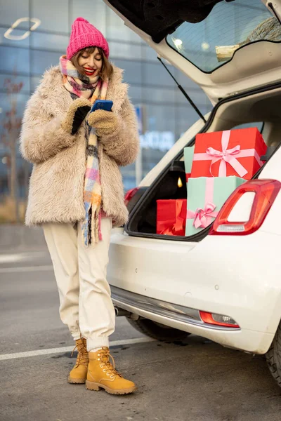 Молодая Веселая Женщина Сидит Телефоном Багажнике Полном Рождественских Подарков Совершая — стоковое фото