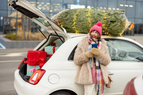 Yukarıda Noel Ağacı Olan Arabanın Yanında Duran Neşeli Bir Kadın — Stok fotoğraf