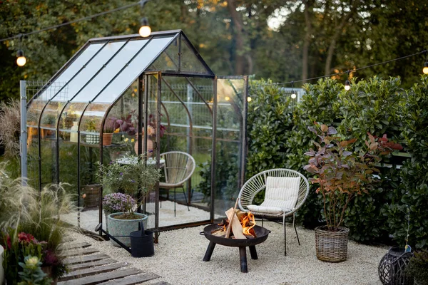 stock image Beautiful and cozy garden with a picnic fire at lounge area and vintage greenhouse behind. Atmospheric and very beautiful courtyard of a country house