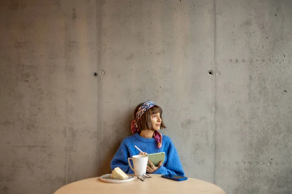 年轻时尚的女人坐在现代咖啡店的混凝土墙背景上 在数字平板电脑上工作 网上远程创作概念 — 图库照片