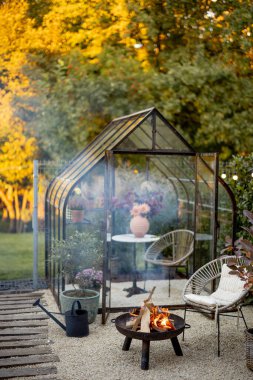 Güzel ve rahat bir bahçe, dinlenme odasında bir piknik ateşi ve arkasında da klasik bir sera var. Atmosferik ve bir kır evinin çok güzel avlusu.