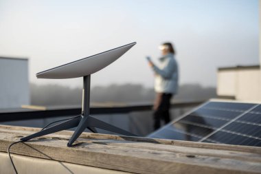 LVIV, UKRAINE - January, 2023: Space X satellite dish, internet constellation operated by SpaceX, installed on roof of residential building equipped with solar panels and woman standing behind