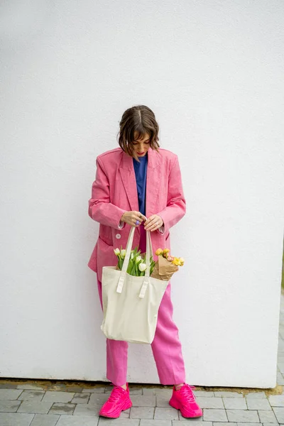 一个穿着粉色西服 头戴绿色手提包 背景为白色花朵的时髦女人的肖像 有空隙的帆布袋 — 图库照片