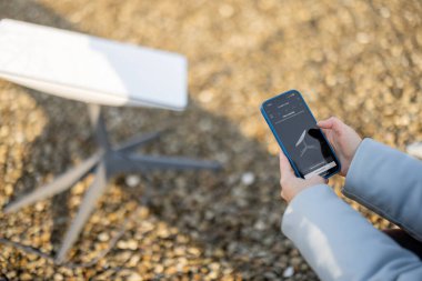 LVIV, UKRAINE - January, 2023: Woman holds phone with running Starlink application for installing satellite internet outdoors during sunny weather