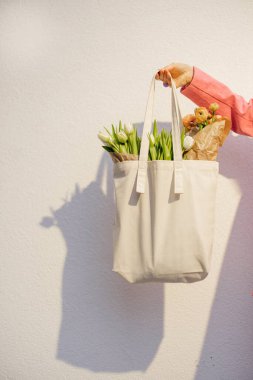 Beyaz arka planda çiçeklerle dolu bir eco çantası, boş boşluklu yakın plan tuval çantası