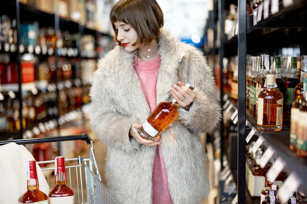 Žena Vybere Silný Alkohol Stojící Nákupním Vozíkem Mezi Řadami Lahví — Stock fotografie