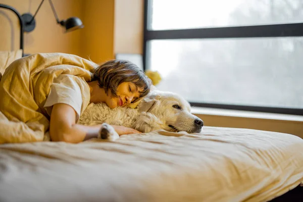 Young Woman Hugs Her Cute Dog While Lying Together Covered — 스톡 사진