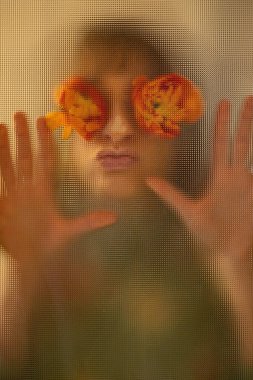 Kadın portresi, gözlerinde çiçekler olan cam bir kapıdan. Güzellik konsepti