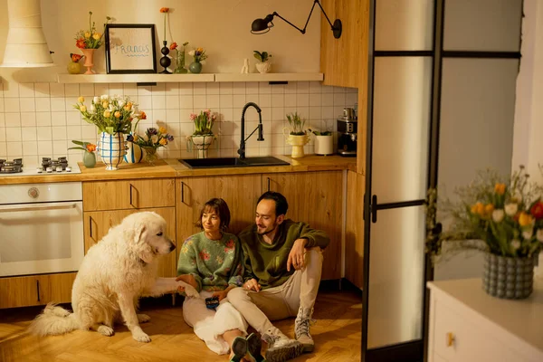 年轻夫妇和一只可爱的狗在厨房里轻松地坐在一起 家庭舒适和家庭生活方式概念 — 图库照片