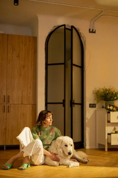 女人和她的狗坐在时尚工作室公寓的厨房地板上 家庭风格和与宠物的友谊概念 — 图库照片