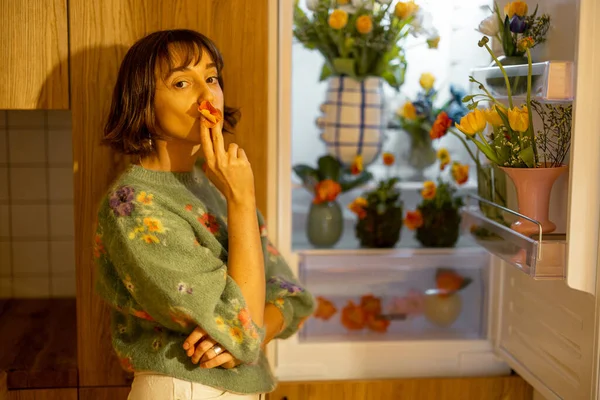 Милая Женщина Открывает Холодильник Наполненный Свежими Цветами Стоя Дома Кухне — стоковое фото