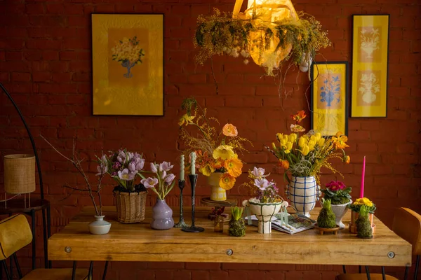 Beautiful dining table decorated with flowers in living room with brick wall and pictures behind