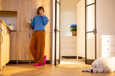 Genç bir kadın modern stüdyo dairesinin mutfağında çaydanlık ve fincanla boş vakitlerini geçirir. Yurtiçi yaşam tarzı ve sağlık konsepti