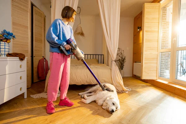 Bir Kadın Evdeki Yatak Odasında Köpeğini Kablosuz Elektrik Süpürgesiyle Süpürüyor — Stok fotoğraf