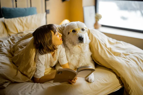 Jovem Mulher Com Seu Cão Bonito Óculos Lendo Livro Enquanto — Fotografia de Stock