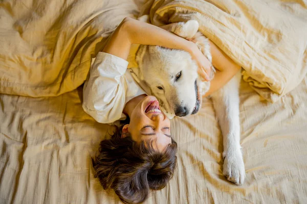 Молодая Женщина Обнимается Своей Милой Собакой Лежа Вместе Покрытые Бежевым — стоковое фото