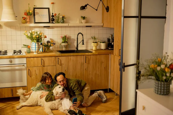 年轻夫妇和一只可爱的狗在厨房里轻松地坐在一起 家庭舒适和家庭生活方式概念 — 图库照片