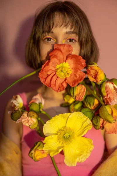 Stock image Portrait of a young woman with island poppy cutted flowers on pink background. Concept of beauty and summer