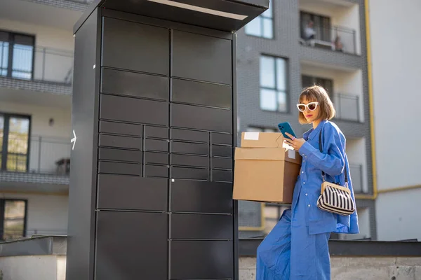 Молода Жінка Забирає Посилки Автоматичної Поштової Машини Стоячи Телефоном Біля — стокове фото