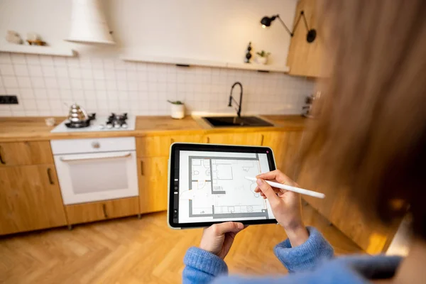 Woman holding touchpad with running program of architectural project, designing kitchen space. Concept of interior design and modern technologies