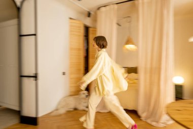 Stüdyonun iç dekorasyonu bej renginde ve hareketlerinde bulanık kadın figürü var.