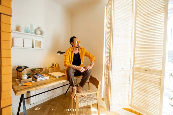 富有创造力的男人坐在木制桌子上 在时尚公寓的工作空间里看书的画像 创意和家庭办公概念 — 图库照片