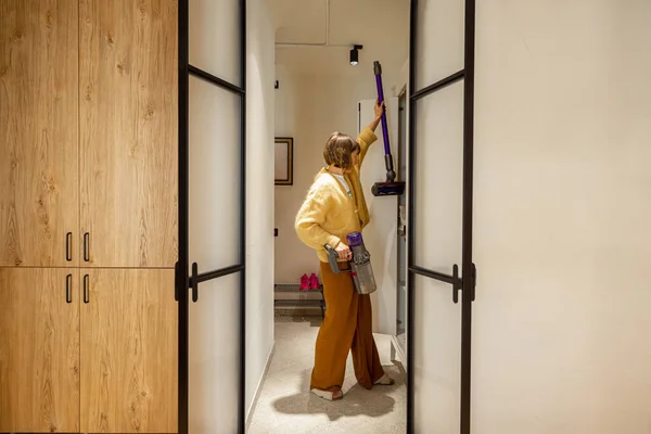 女人在现代公寓的走廊里从衣柜里拿吸尘器 从拱门看过去 家庭日常事务和家务活概念 — 图库照片