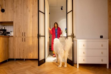 Köpek, ev sahibini oturma odasının kapısında karşılar. Evcil hayvanlarınız sizi beklerken mutlu bir eve dönüş kavramı. Geniş iç görünüm