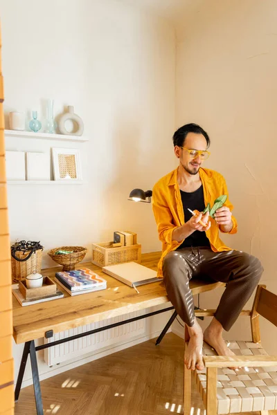 富有创造力的男人坐在木制桌子上 在时尚公寓的工作空间里看书的画像 创意和家庭办公概念 — 图库照片