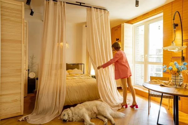 女人在舒适的卧室里做家务活的时候会铺床 而狗则睡在前面 — 图库照片