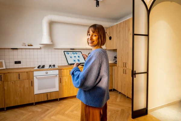 一个女人的肖像带着一个数字平板电脑 有运行智能家庭程序 控制智能厨房用具 舒适生活新技术的概念 — 图库照片