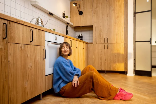 年轻女子坐在新的时尚工作室公寓的厨房地板上 新家庭内部和家庭休闲的概念 — 图库照片