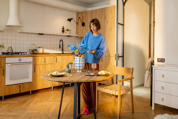 女人用花瓶装饰餐桌 在现代风格的工作室公寓里做家务活 — 图库照片