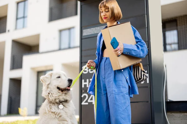 Молода Жінка Збирає Посилки Автоматичної Пошти Стоячи Своєю Собакою Біля — стокове фото